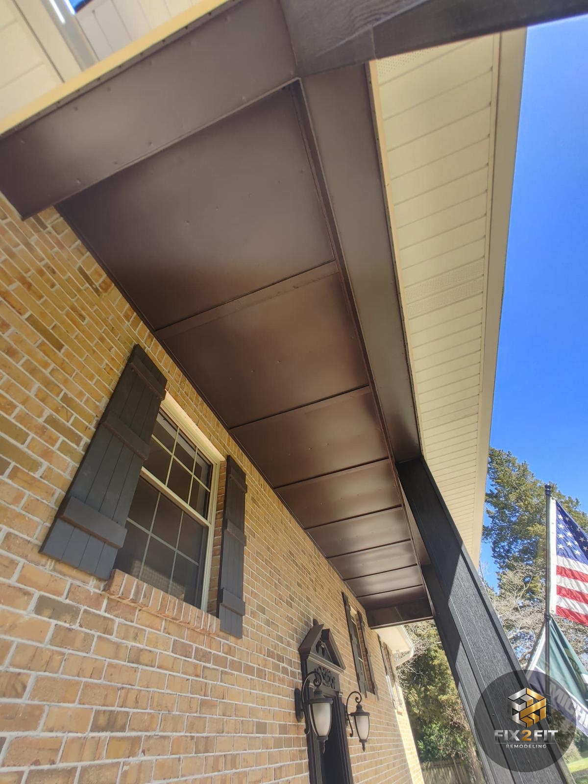 Repainted fascia and soffit along the roofline of a brick home